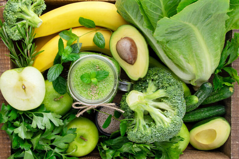 Raw Foods for Healthy Skin - picture shows a variety of healthy raw foods including bananas, broccoli, avocado, apples, romaine lettuce and a green smoothie