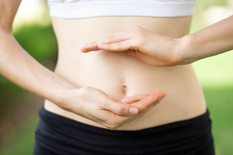 Woman with her hands hovering over one another in front of her belly button